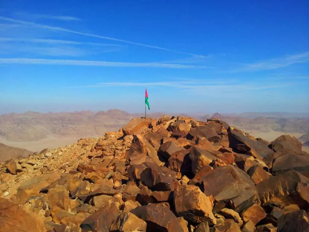 Hiker standing on a rocky peak overlooking the vast desert landscape of Wadi Rum