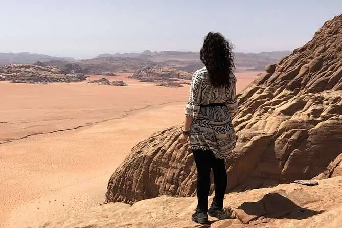 Woman standing on a rock overlooking the vast desert of Wadi Rum at Jebel Haash