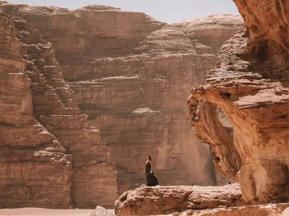 Traveler sitting beneath towering rock formations in the Wadi Rum desert