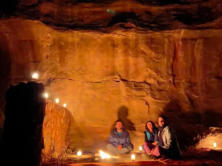 A guest sitting by the fire in a cave-like setting at night in Wadi Rum, enjoying the warmth and silence of the desert.
