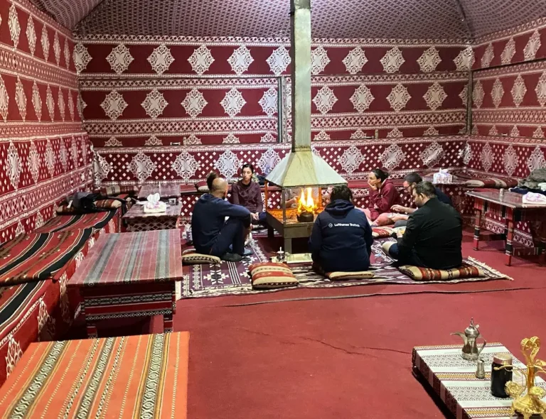 Traditional Bedouin tent interior at Salem Camp in Wadi Rum with colorful carpets and cozy seating.